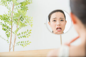 自分の歯や歯ぐきを鏡で確認する女性