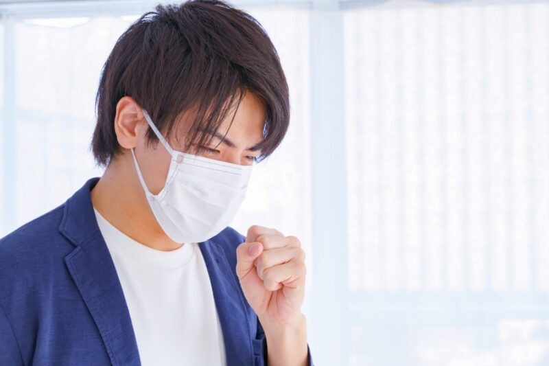 咳をするマスク姿のアジア人男性