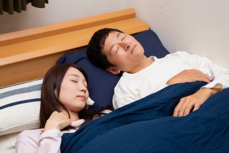 ベッドで仲良く寝ている若い夫婦