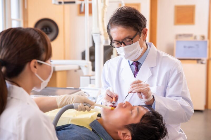 患者を治療する医師と歯科衛生士