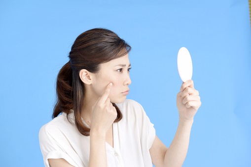 鏡で肌を確認する女性